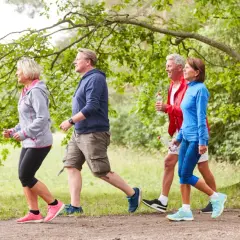 Persone di mezza età camminano in un parco. Anche con artrosi ai piedi, camminare fa bene per mantenersi attivi e in salute.