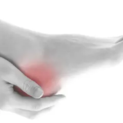 Mano che massaggia un tallone arrossato, indicando dolore ai talloni a letto.