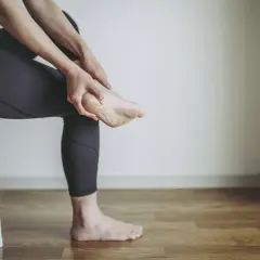 Persona che si massaggia il tallone, forse per un dolore o per le cause di un male al tallone.