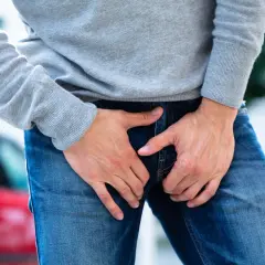 Uomo con le mani nella zona inguinale, che esprime disagio per un dolore all'attaccatura della gamba.