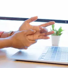 Mano che si massaggia il polso, forse per un dolore osso del polso causato dall'uso del computer.
