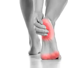Donna si tocca il tallone, evidenziato in rosso, per indicare il dolore tallone laterale interno.