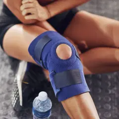 Donna con tutore al ginocchio blu, seduta su pavimento gommato. Considerare le controindicazioni del tutore ginocchio prima dell'uso.