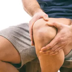 Uomo con mani sul ginocchio, segno di sovraccarico ginocchio e lunghi tempi di recupero.