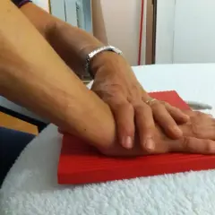 Mani che si appoggiano su un tappetino rosso, un gesto che può far parte dei rizoartrosi rimedi per alleviare il dolore.