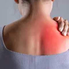 Donna con mano sulla spalla sinistra, evidenziata in rosso, per indicare bruciore sotto la scapola sinistra: cause e rimedi.