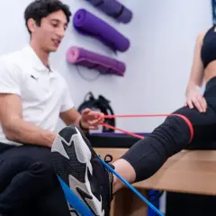 Fisioterapista assiste paziente in esercizi con elastici per contrastare il ginocchio valgo.