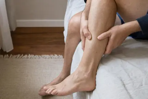Uomo che si massaggia il polpaccio, forse per alleviare la sensazione di nervi accavallati.