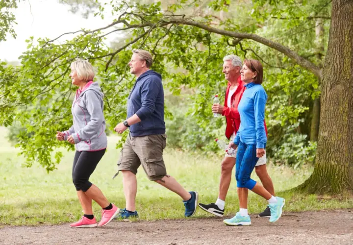 Persone di mezza età camminano in un parco. Anche con artrosi ai piedi, camminare fa bene per mantenersi attivi e in salute.