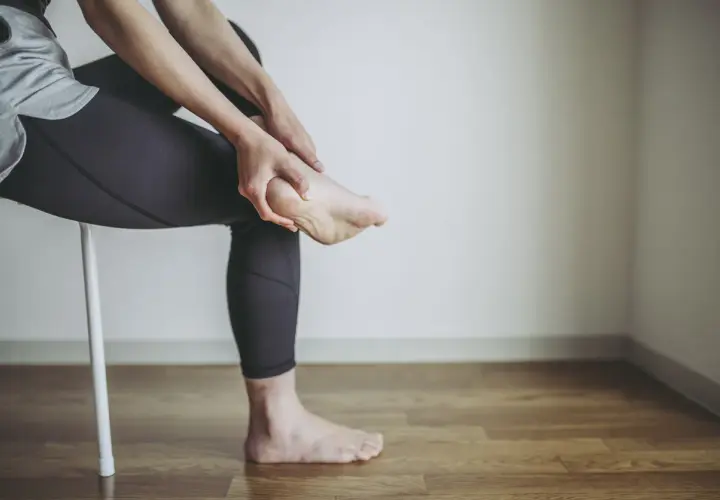 Persona che si massaggia il tallone, forse per un dolore o per le cause di un male al tallone.