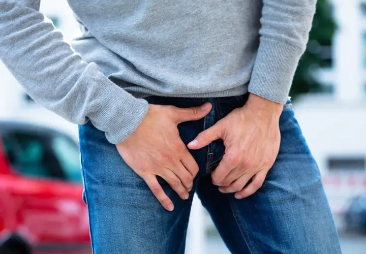 Uomo con le mani nella zona inguinale, che esprime disagio per un dolore all'attaccatura della gamba.
