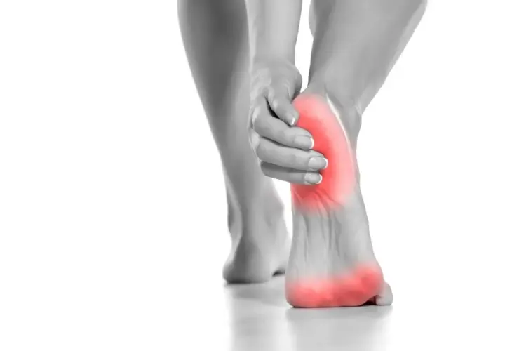 Donna si tocca il tallone, evidenziato in rosso, per indicare il dolore tallone laterale interno.