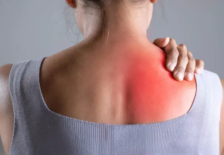 Donna con mano sulla spalla sinistra, evidenziata in rosso, per indicare bruciore sotto la scapola sinistra: cause e rimedi.