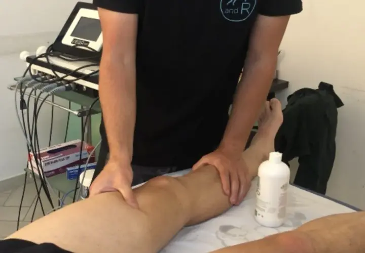 Fisioterapista massaggia un ginocchio, forse per alleviare i sintomi di calcificazione al ginocchio.