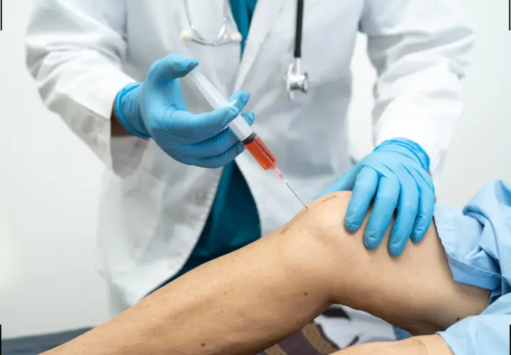 Medico in guanti blu inietta PRP nel ginocchio di un paziente. La terapia PRP può accelerare i tempi di recupero.