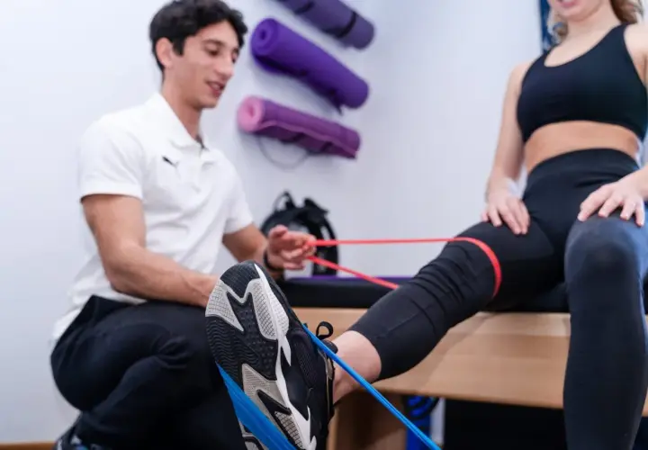 Fisioterapista assiste paziente in esercizi con elastici per contrastare il ginocchio valgo.