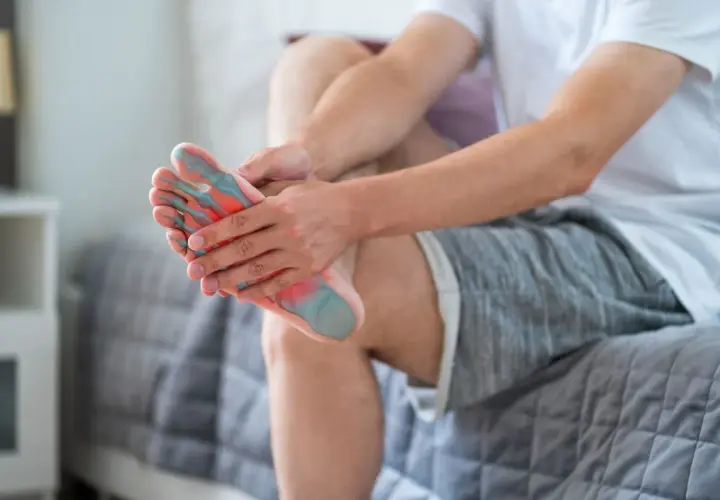 Uomo con dolore al piede, evidenziate aree di infiammazione che potrebbero indicare borsite malleolo.