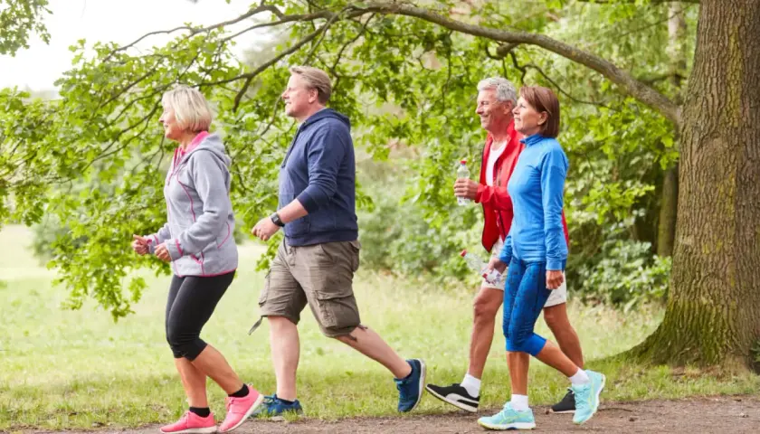 Persone di mezza età camminano in un parco. Anche con artrosi ai piedi, camminare fa bene per mantenersi attivi e in salute.