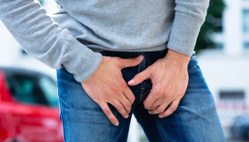 Uomo con le mani nella zona inguinale, che esprime disagio per un dolore all'attaccatura della gamba.