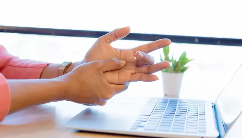 Mano che si massaggia il polso, forse per un dolore osso del polso causato dall'uso del computer.