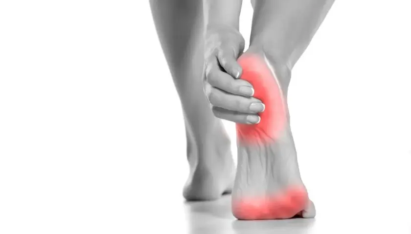 Donna si tocca il tallone, evidenziato in rosso, per indicare il dolore tallone laterale interno.