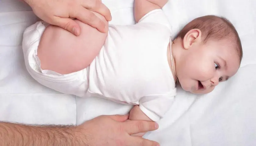 Mani adulte che controllano le anche di un neonato, un esame per la displasia dell'anca.