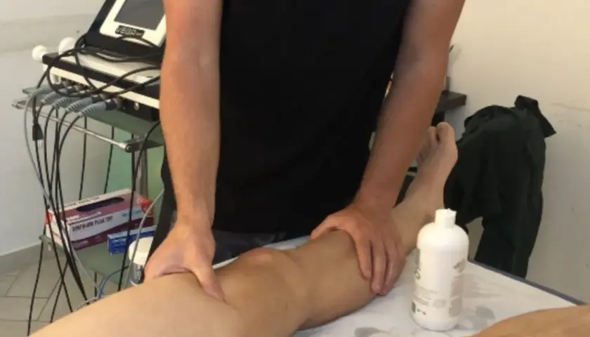 Fisioterapista massaggia un ginocchio, forse per alleviare i sintomi di calcificazione al ginocchio.