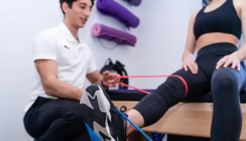 Fisioterapista assiste paziente in esercizi con elastici per contrastare il ginocchio valgo.