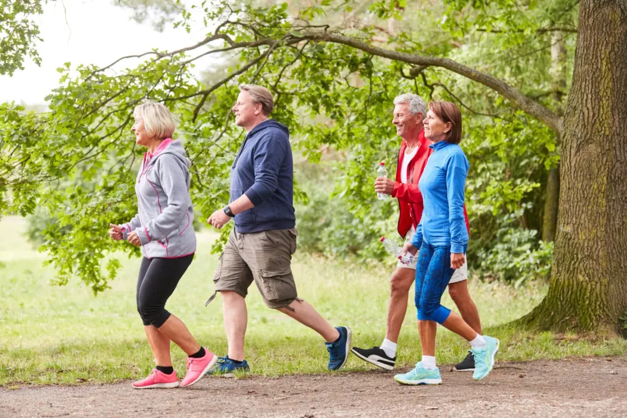 Persone di mezza età camminano in un parco. Anche con artrosi ai piedi, camminare fa bene per mantenersi attivi e in salute.
