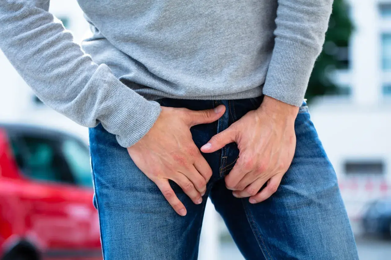 Uomo con le mani nella zona inguinale, che esprime disagio per un dolore all'attaccatura della gamba.