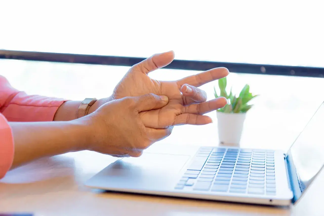 Mano che si massaggia il polso, forse per un dolore osso del polso causato dall'uso del computer.
