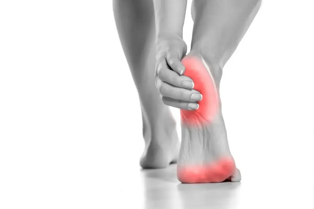 Donna si tocca il tallone, evidenziato in rosso, per indicare il dolore tallone laterale interno.