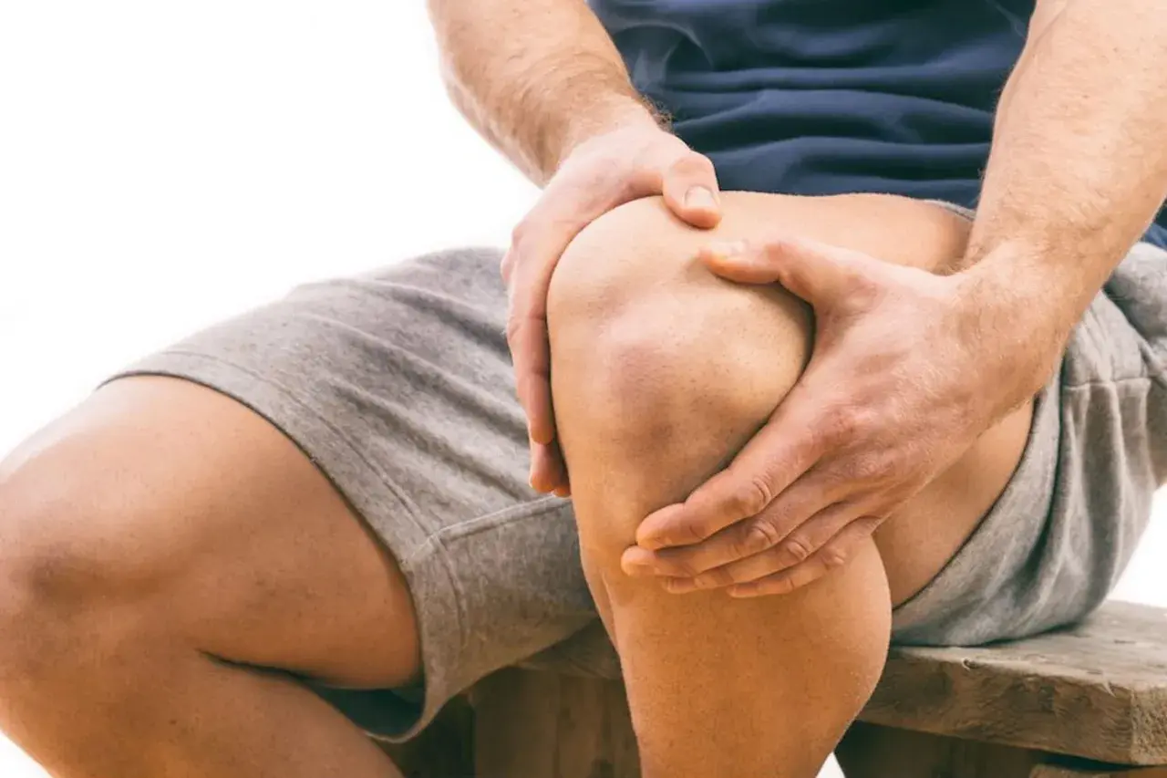 Uomo con mani sul ginocchio, segno di sovraccarico ginocchio e lunghi tempi di recupero.